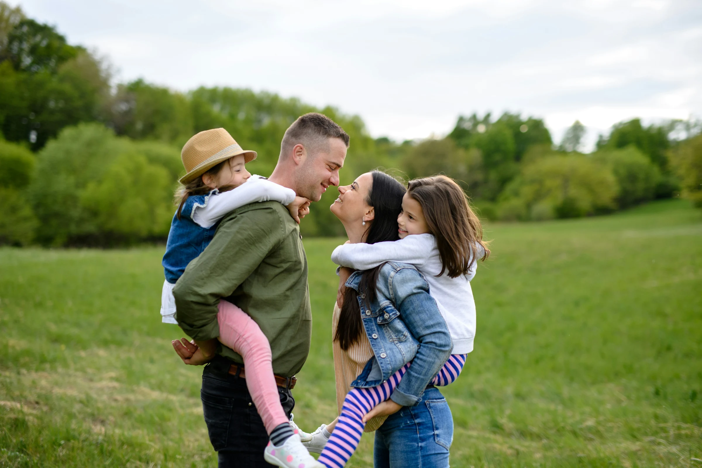 A family pausing together with the children riding on their parents’ backs.